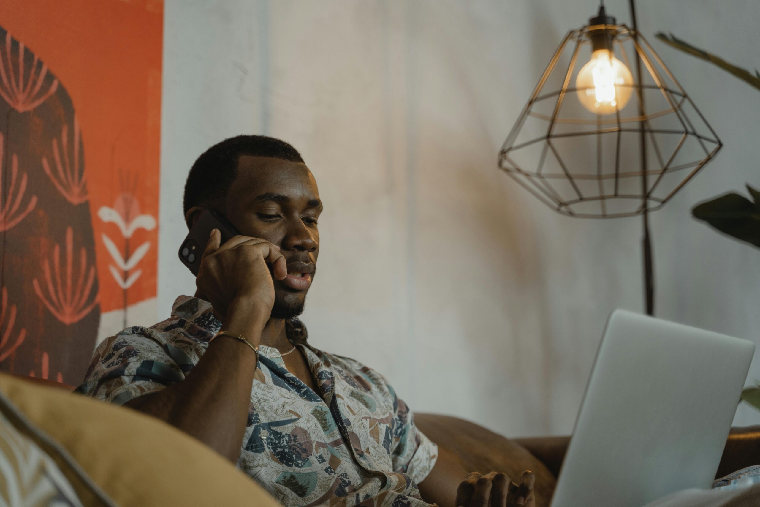 Man in Gray and Black Floral Button Up Shirt Sitting on Brown Couch