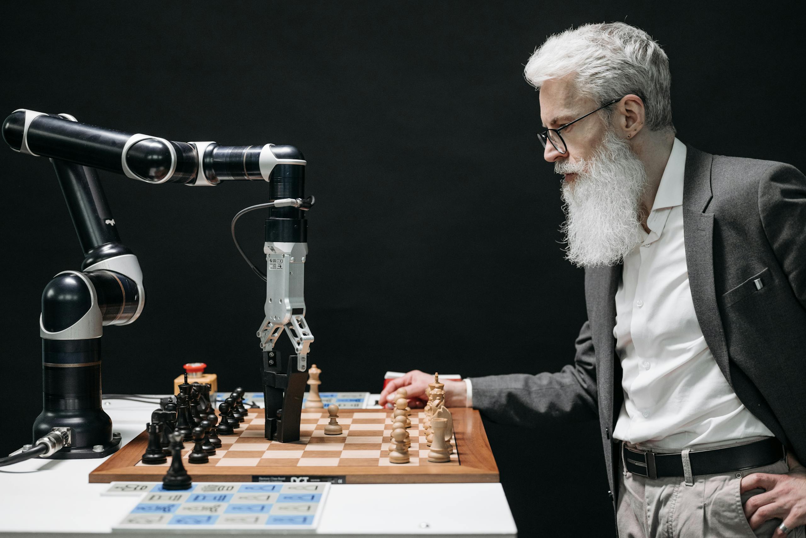 A man plays chess against an AI robotic arm, showcasing technology and strategy innovation.