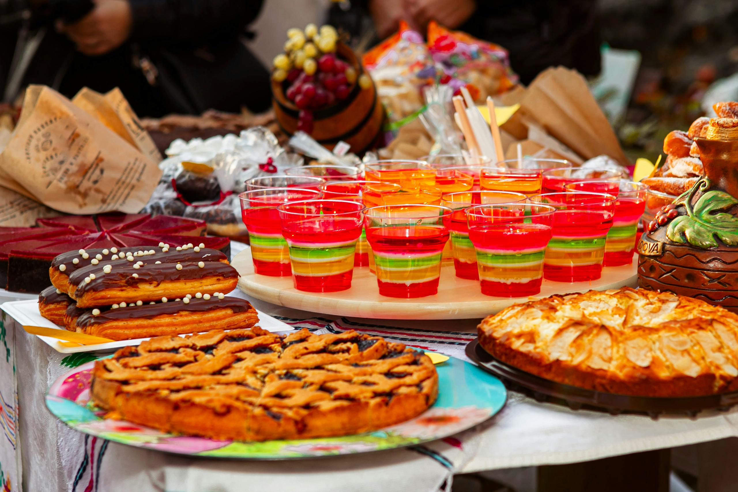 A vibrant display of desserts including pastries and colorful jellies at an outdoor market.