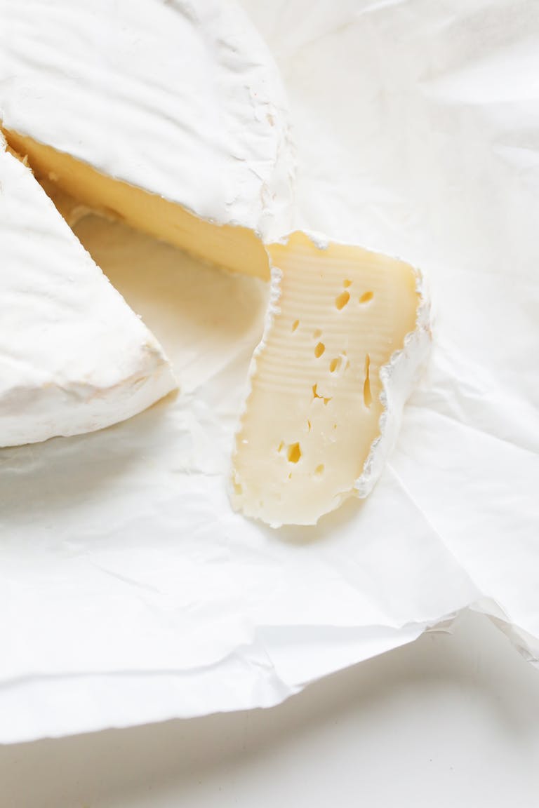 Close-up shot of creamy brie cheese on white parchment paper.
