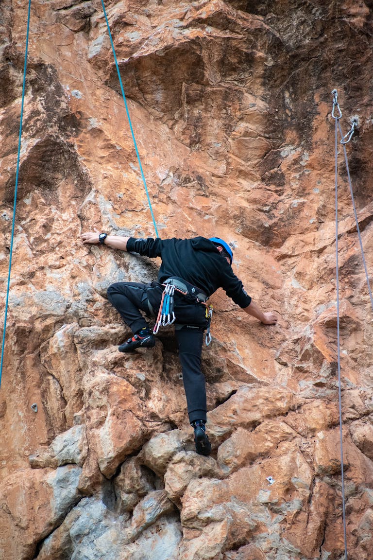 Man engaged in rock climbing on rugged cliff in Kaiafas, Greece, showing adventure and determination.