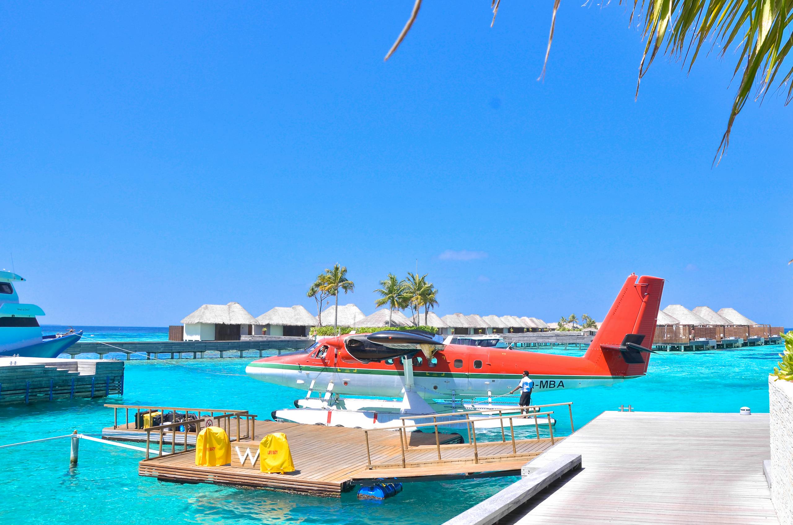 Seaplane docked at a vibrant tropical island resort under a clear blue sky, perfect for vacations.