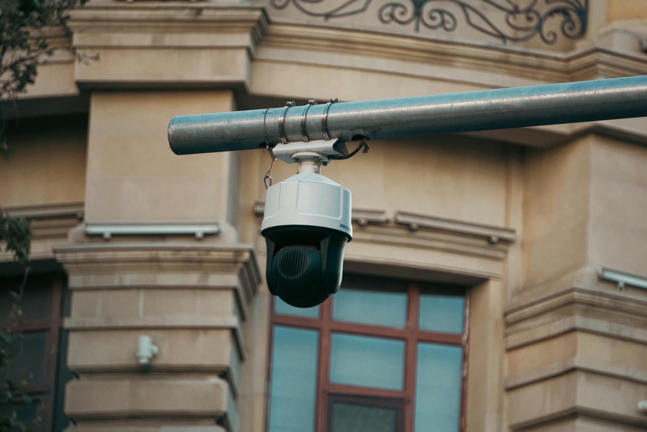 Close-up of a surveillance camera mounted on an urban building exterior, highlighting security.