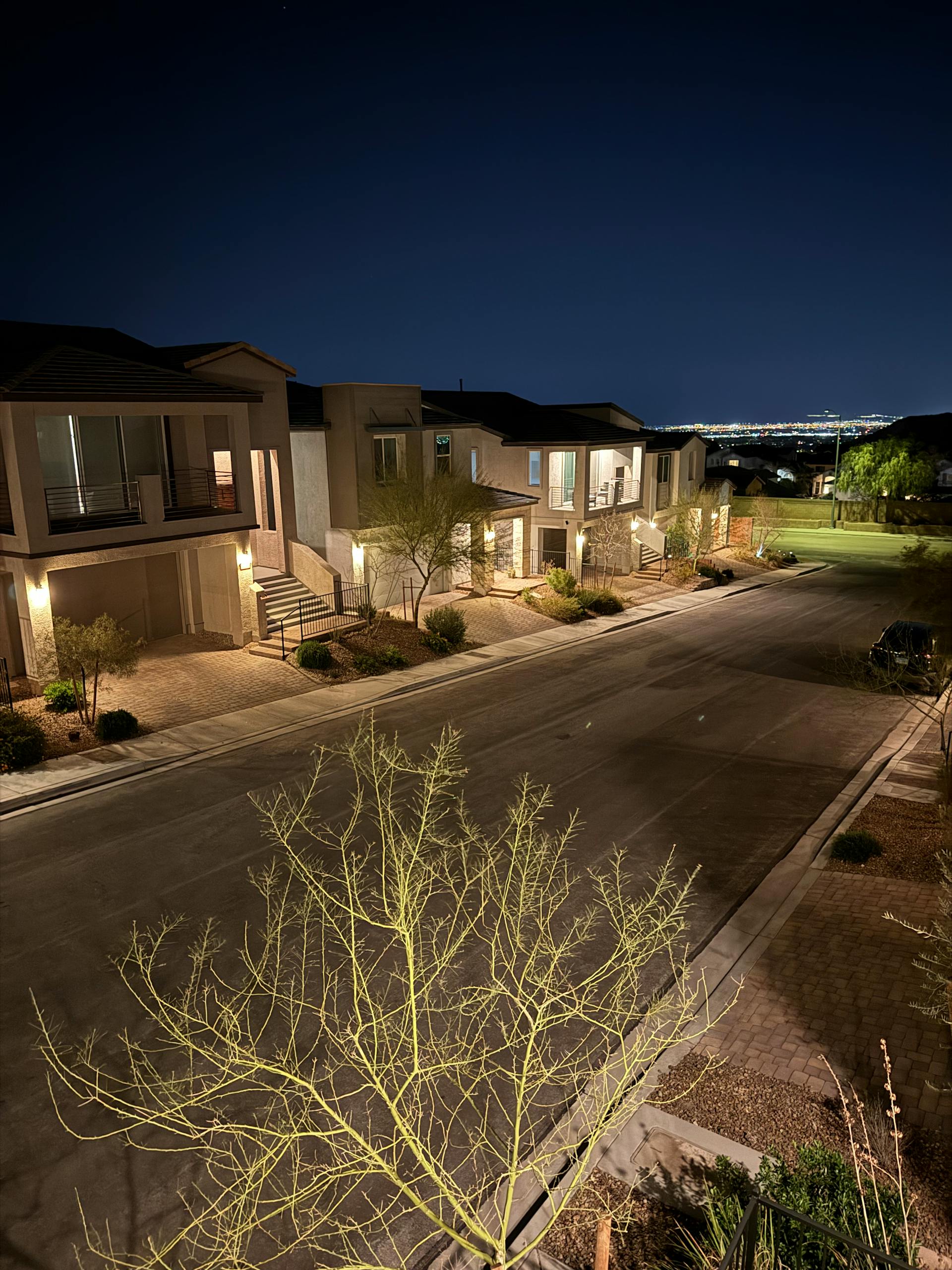 A peaceful, well-lit suburban street in Las Vegas at night, showcasing modern architecture.