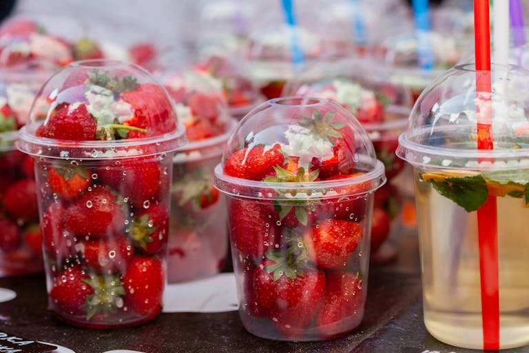 Close-up of fresh strawberries in clear plastic cups, ideal for food presentations.