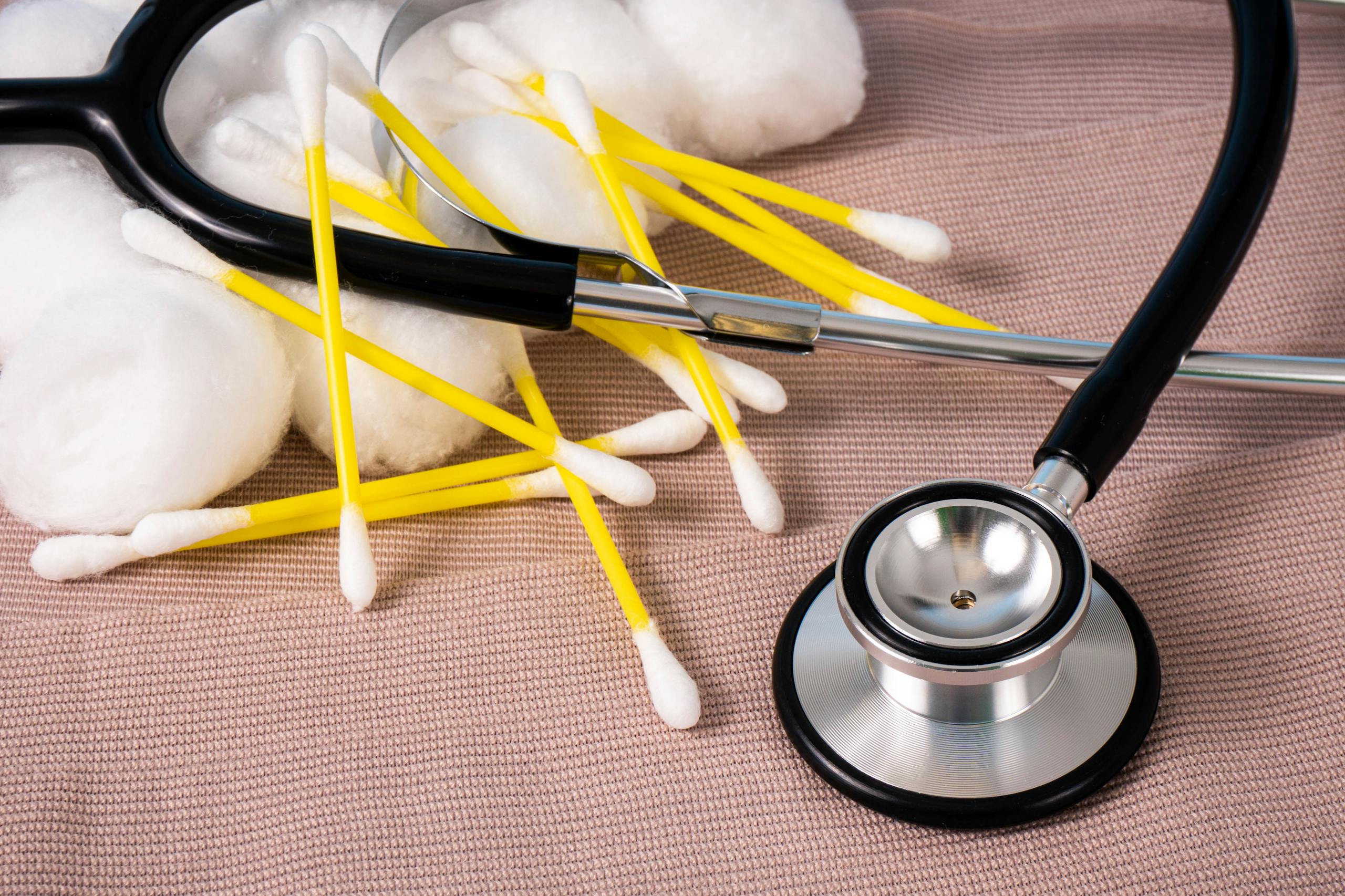 Detailed image of cotton swabs and a stethoscope on a textile surface, ideal for healthcare themes.