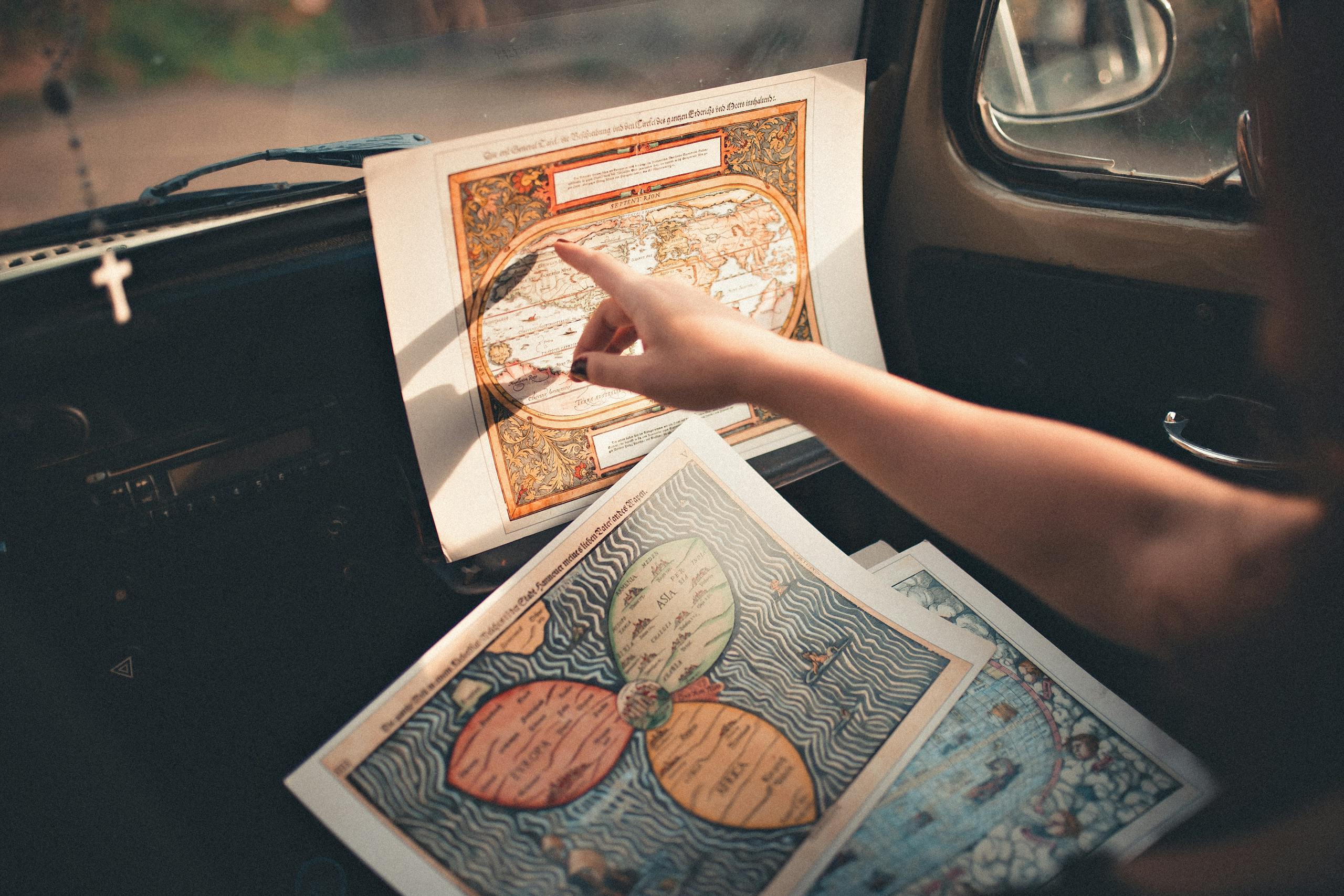 Vintage car interior with a woman examining old maps, capturing a sense of adventure and exploration.
