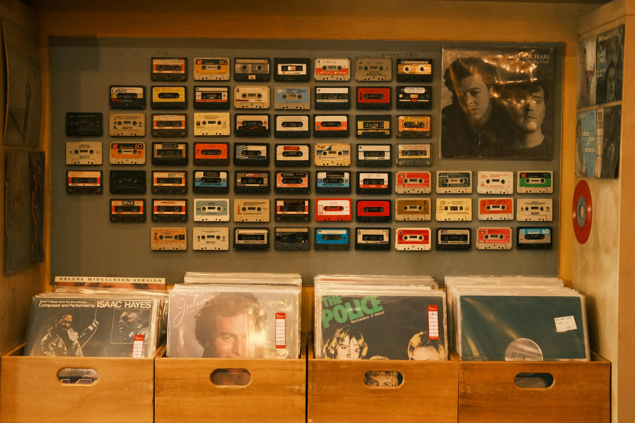 A nostalgic wall of cassettes above vinyl records in a vintage music store.
