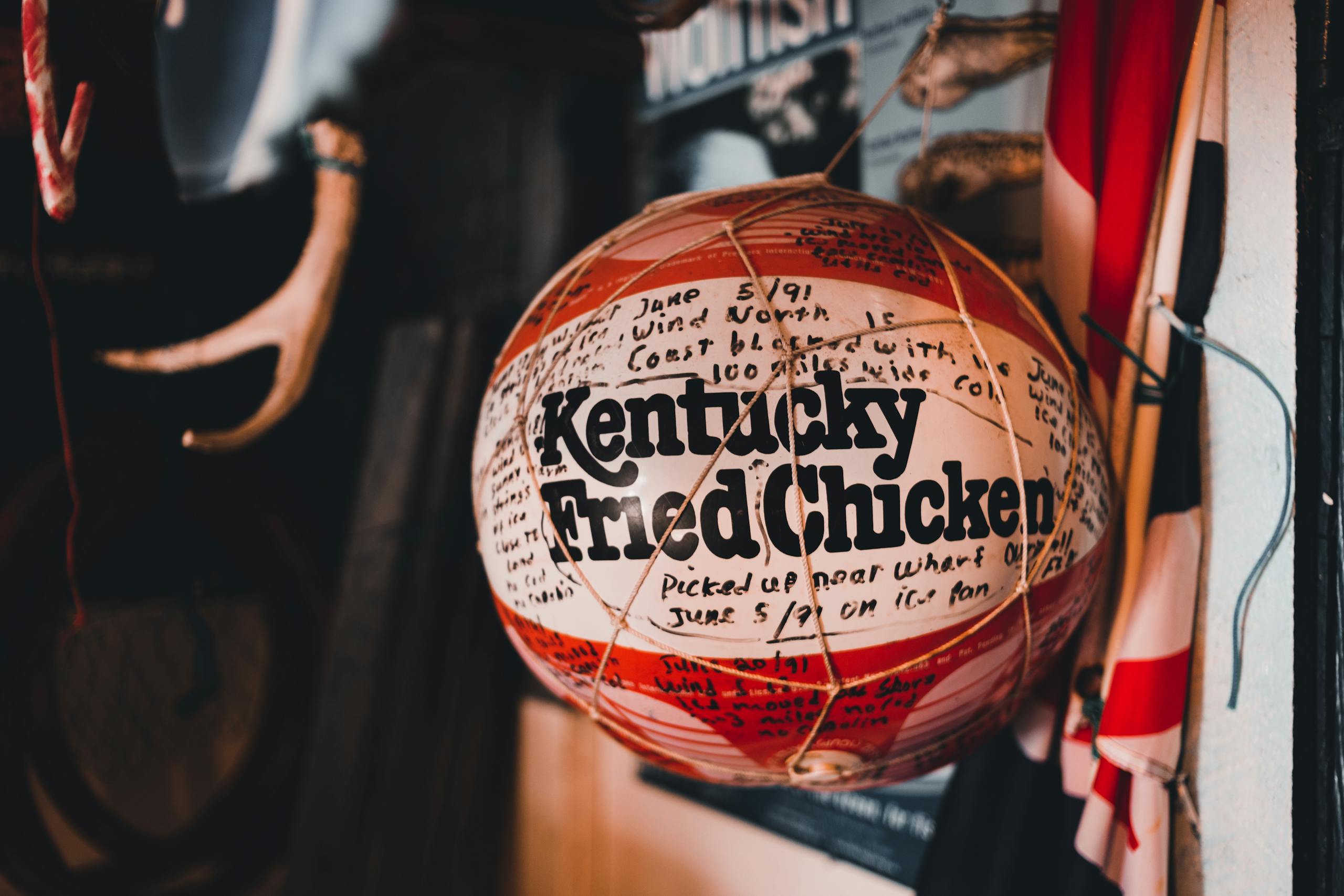 A vintage basketball with Kentucky Fried Chicken branding hangs indoors, surrounded by eclectic decor.