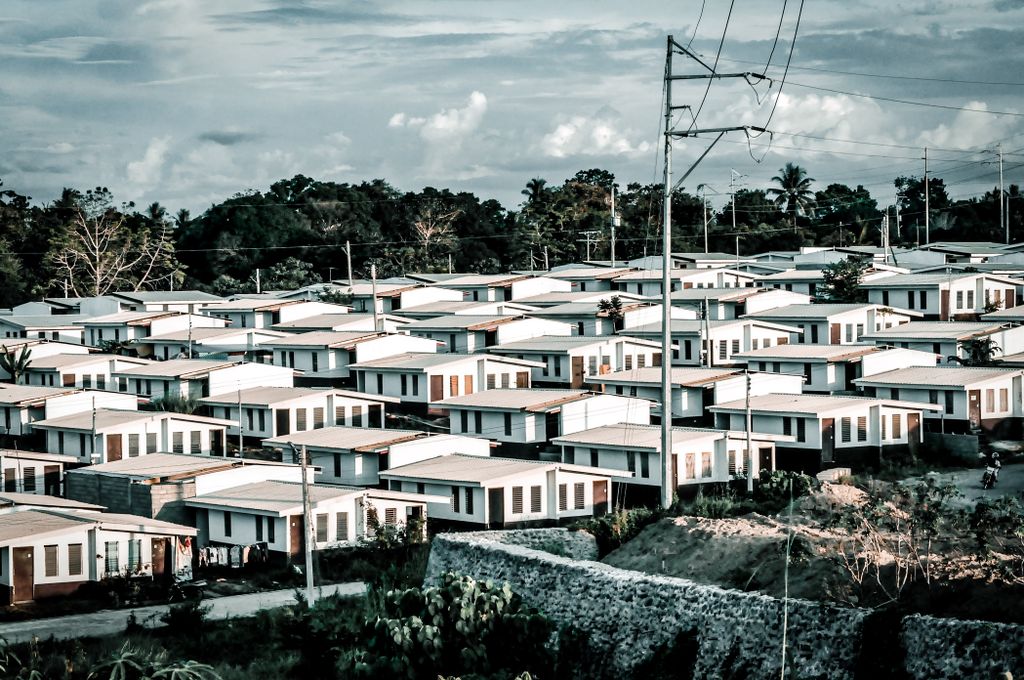 Aerial shot of a modern suburban housing area with identical homes under a cloudy sky.