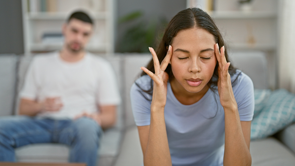 Stressed beautiful couple arguing on sofa, battling headaches at home