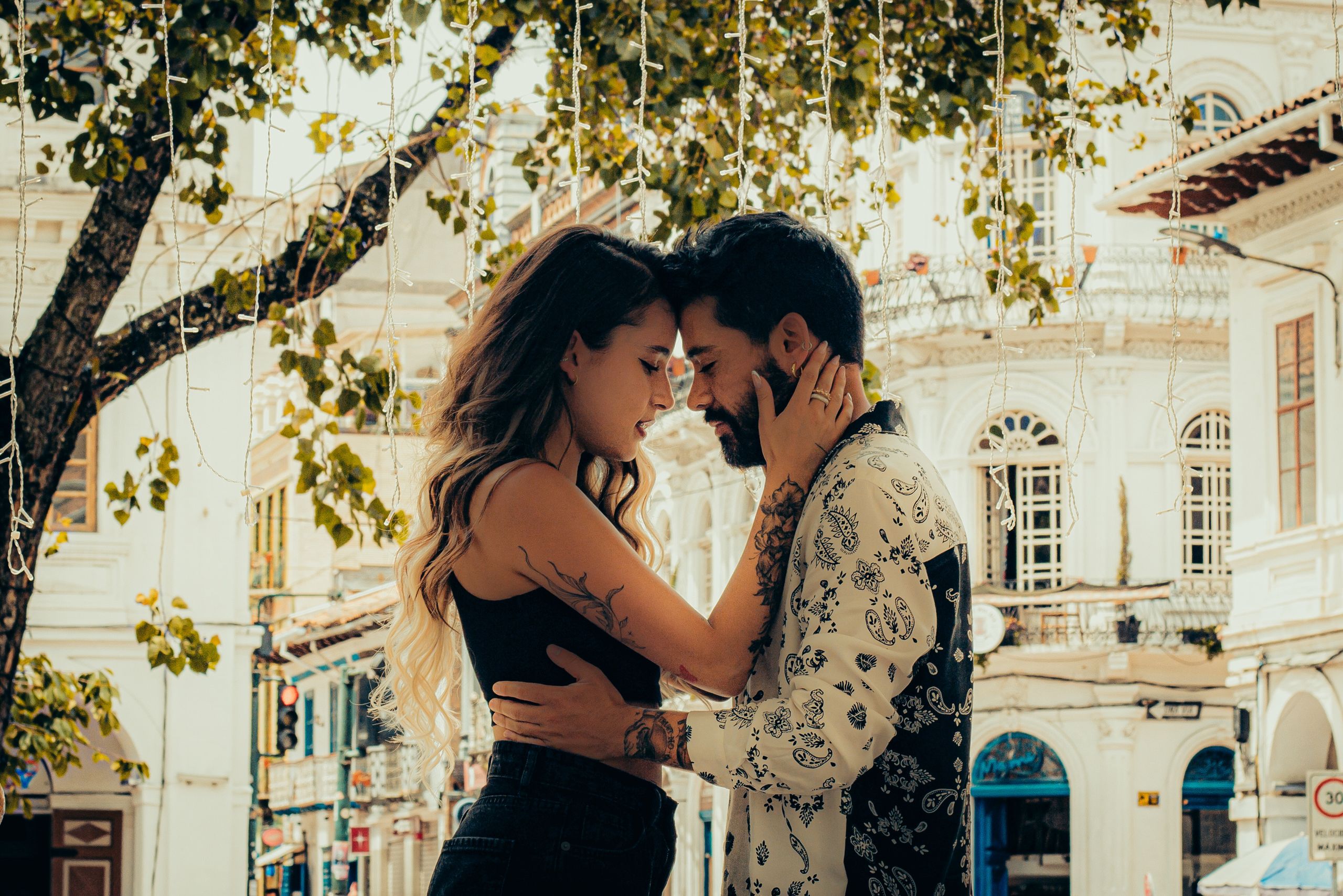 A couple shares a heartfelt moment amid a charming Ecuadorian street adorned with trees.