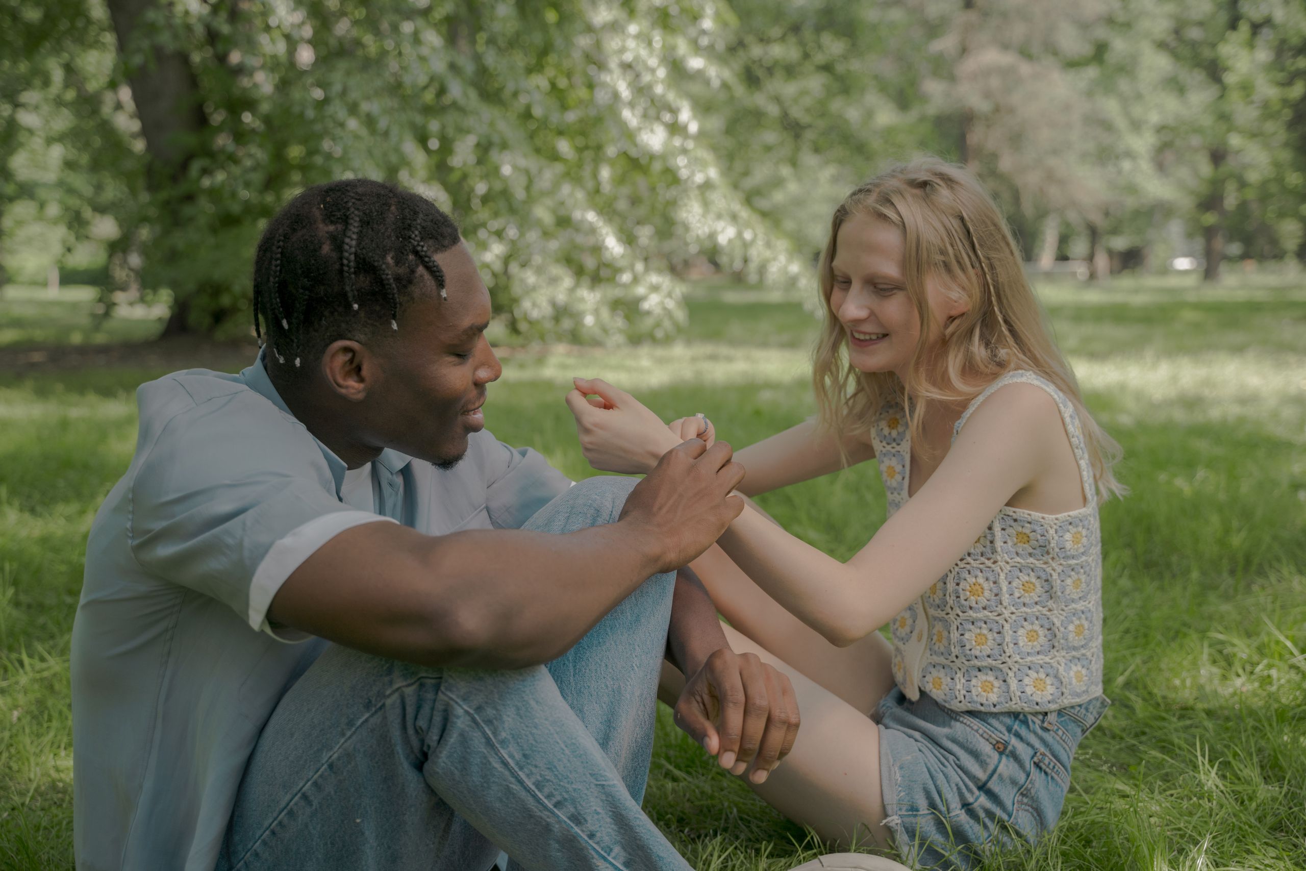 A diverse couple sitting and enjoying the outdoors in a sunny park.