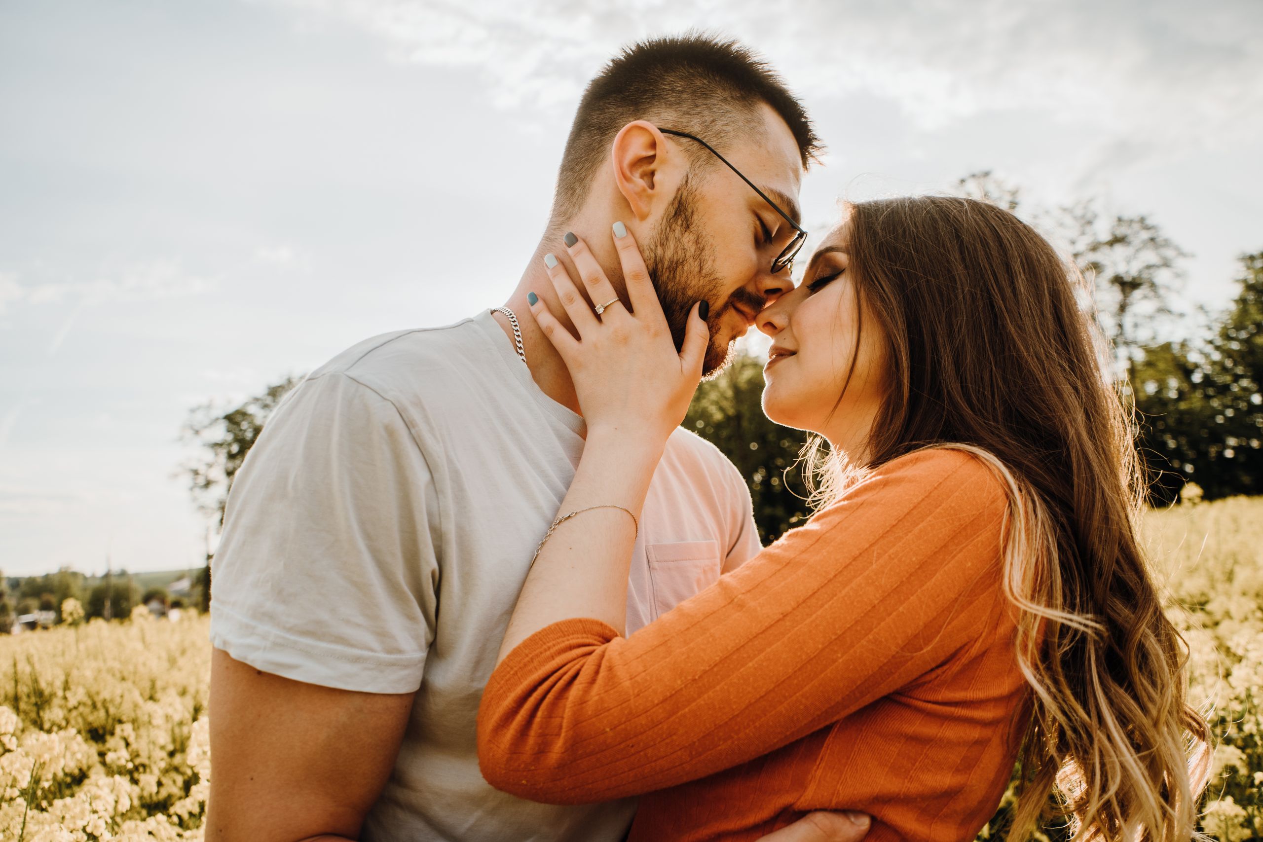 A loving couple sharing an intimate moment in a sunlit field, epitomizing romance and connection.