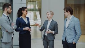 Business professionals in suits discussing strategy in a modern office.