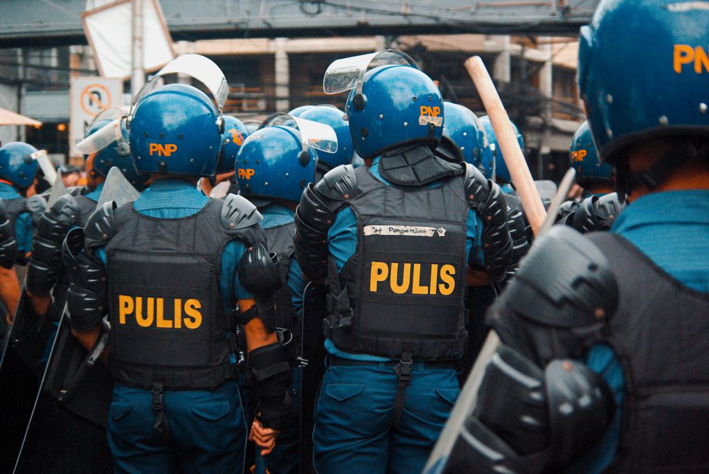 Riot police in blue uniforms and helmets gather for a street demonstration response.
