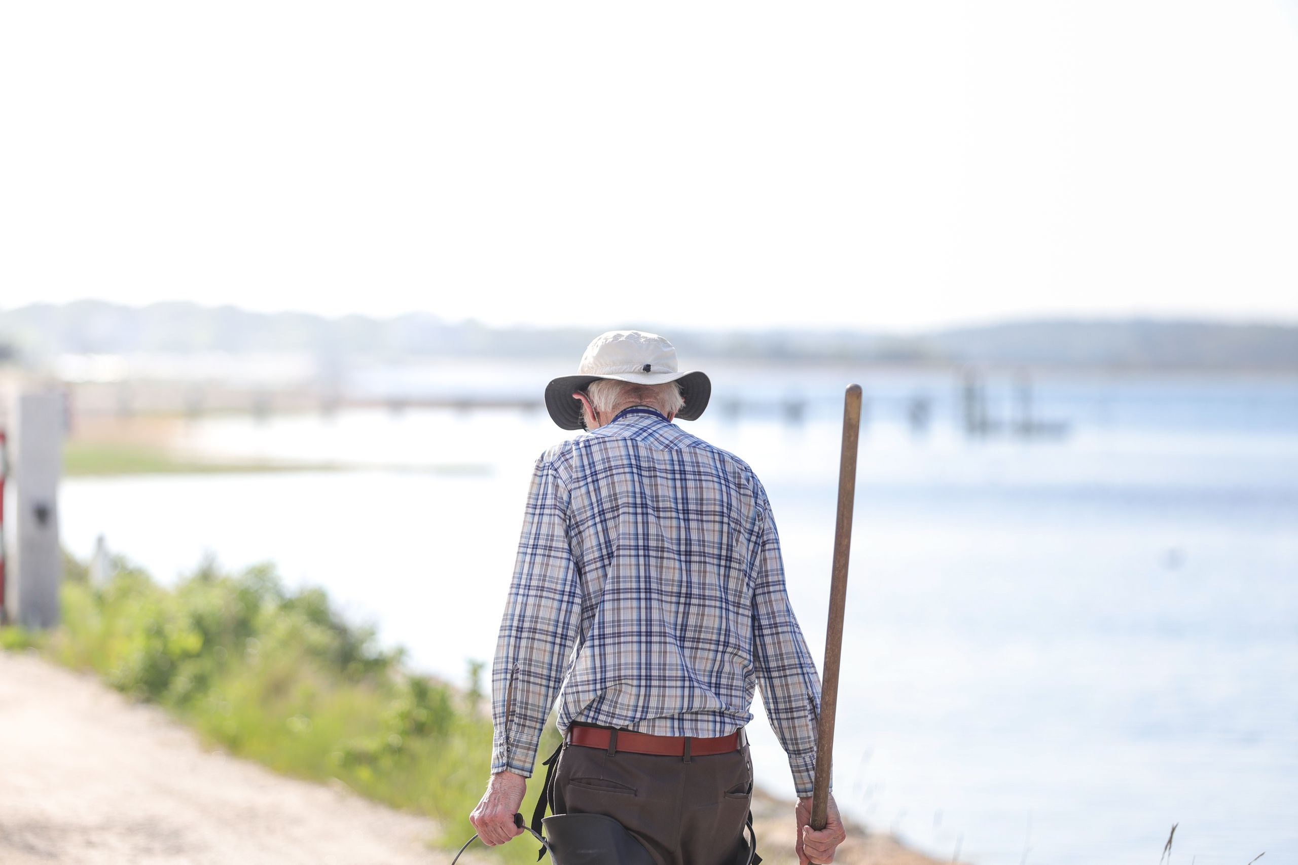 A senior man strolls by the water in Bourne, Massachusetts on a sunny day.