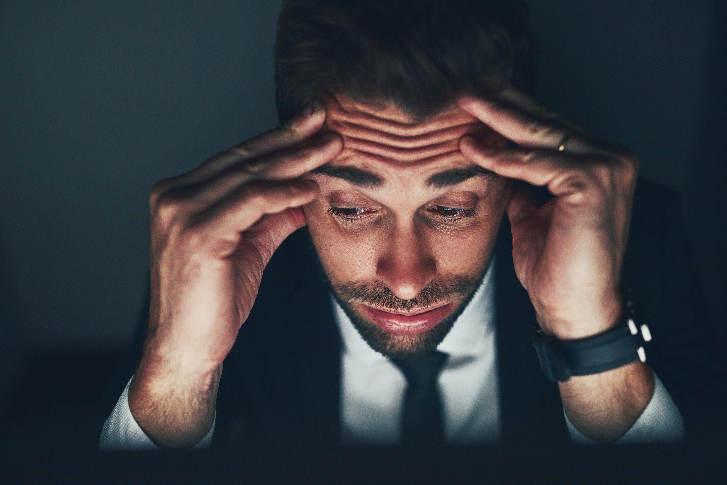 The stress is getting to him. a young businessman looking stressed while working late in the office. man thinking