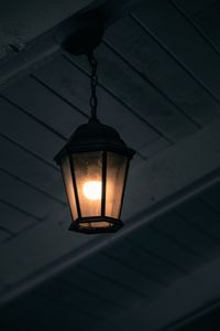 A close-up of a vintage lantern casting a warm glow on a wooden ceiling. Atmospheric night lighting.