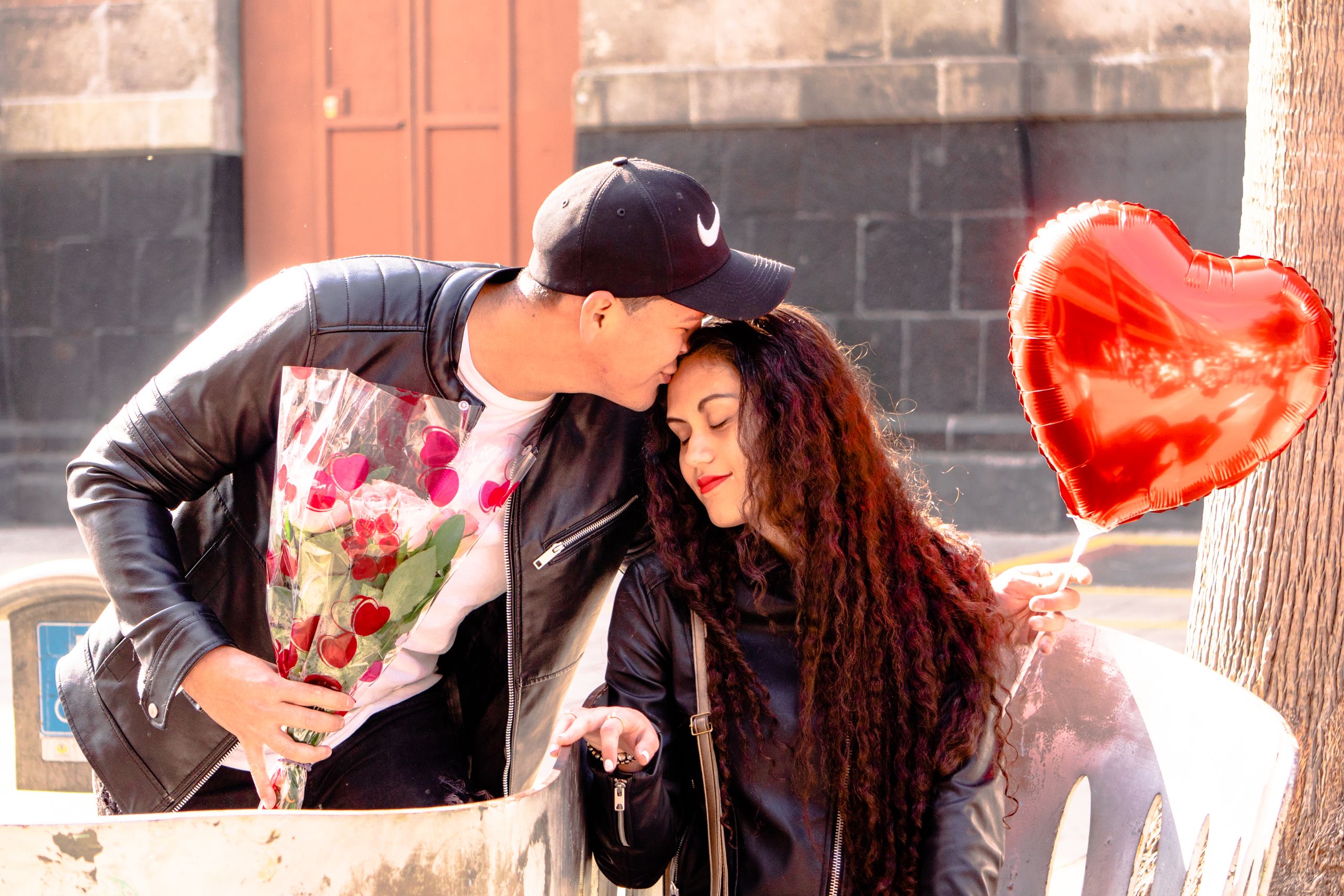 A couple shares a tender moment with flowers and a heart-shaped balloon in Mexico City.