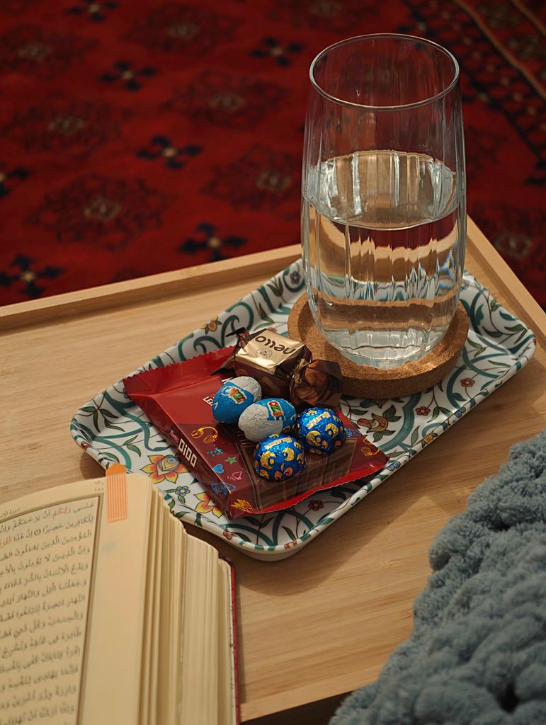 A cozy reading spot with a book, water, and chocolate treats on a decorative tray.