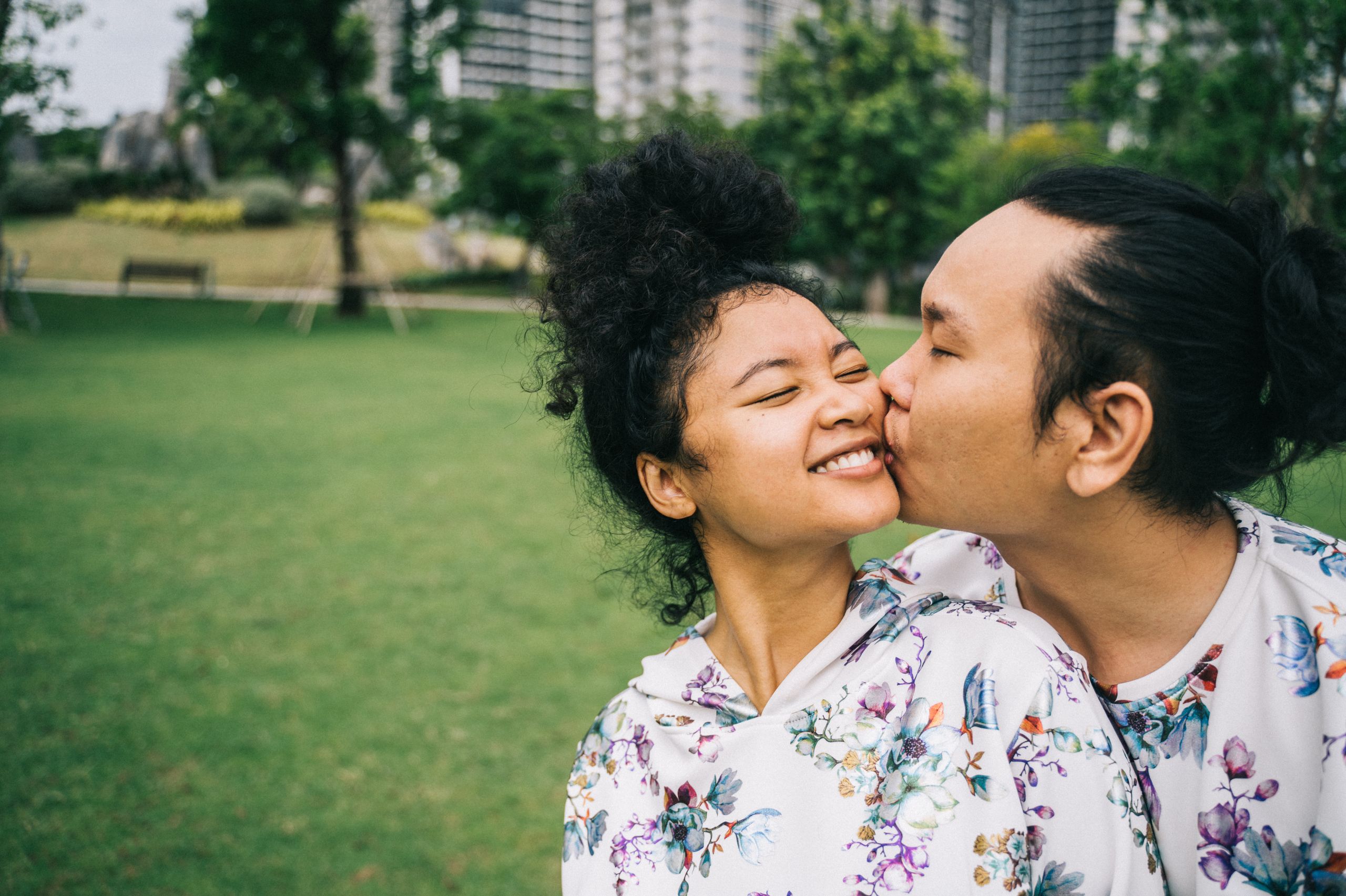 A happy couple sharing a loving moment in a scenic park landscape.