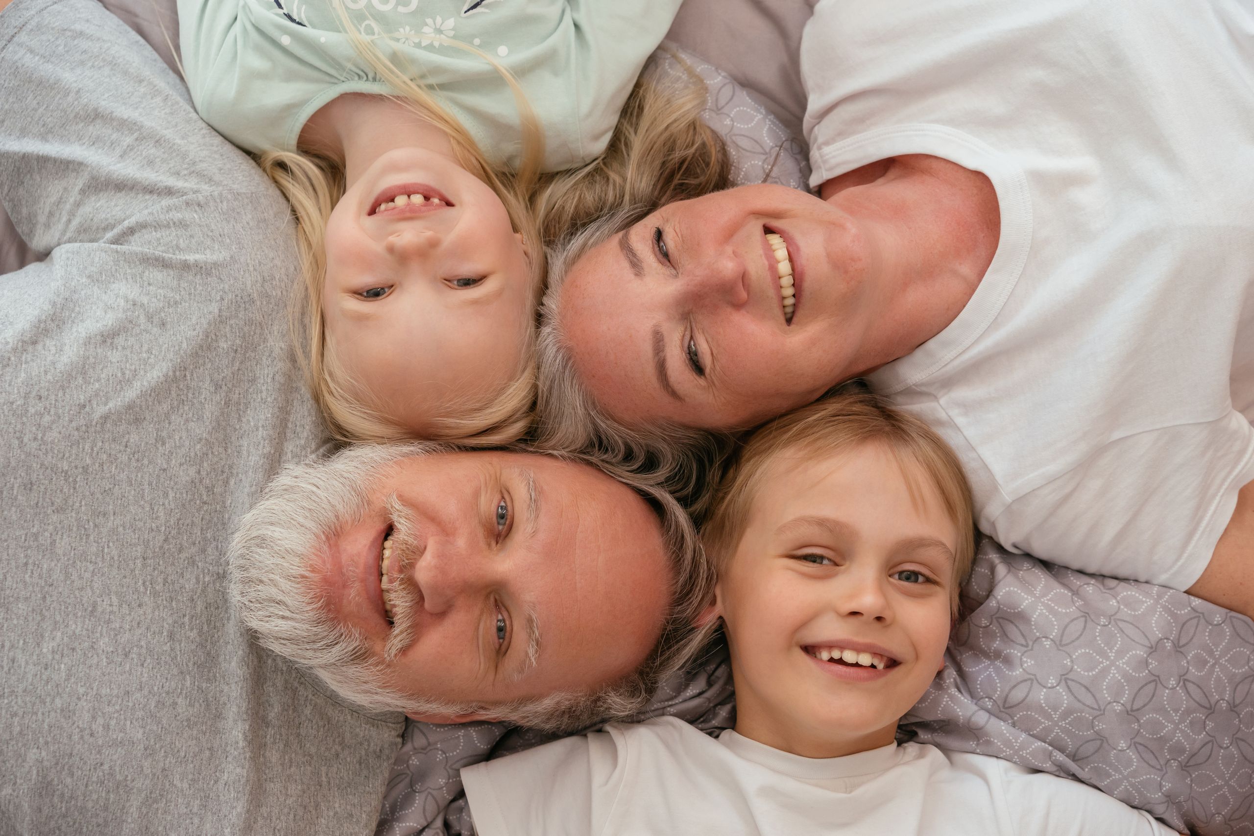 A joyful multigenerational family lying down and smiling together, displaying warmth and affection.