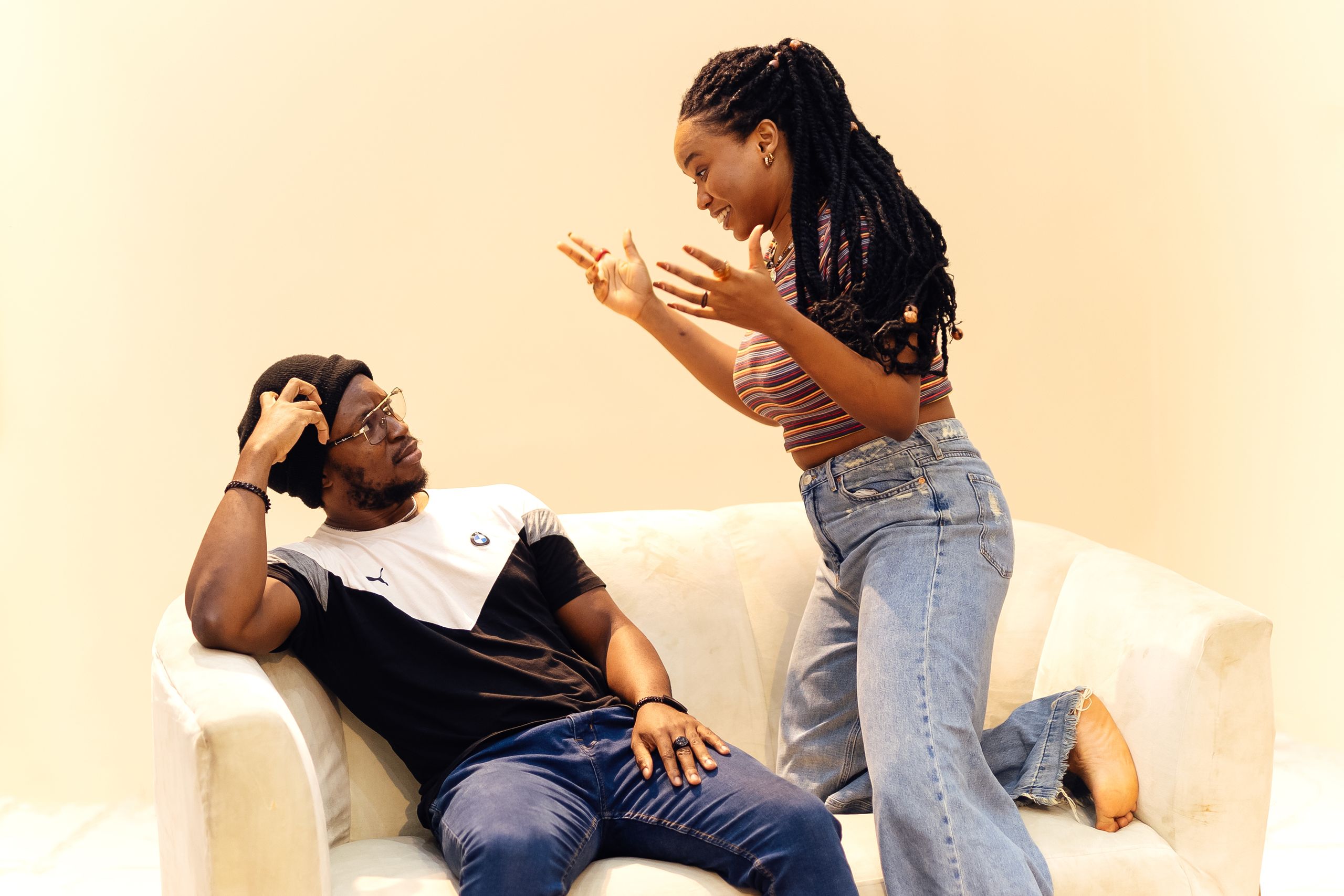 A lively conversation between a couple sitting and standing on a couch in a modern living room.