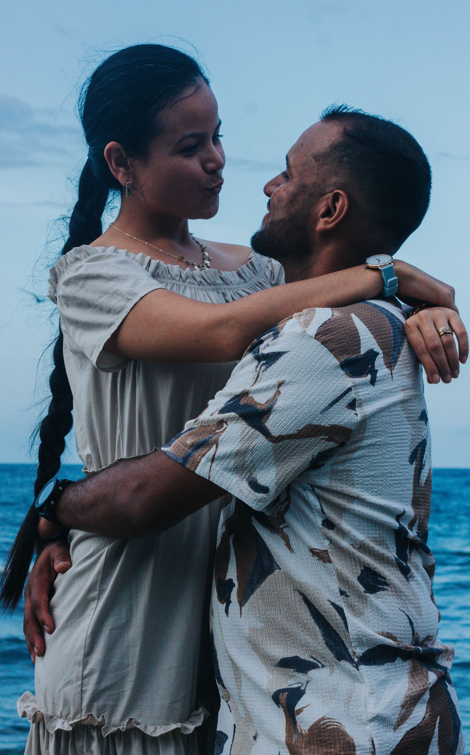 A loving couple embraces by the sea in Venezuela, capturing a moment of joy and connection.