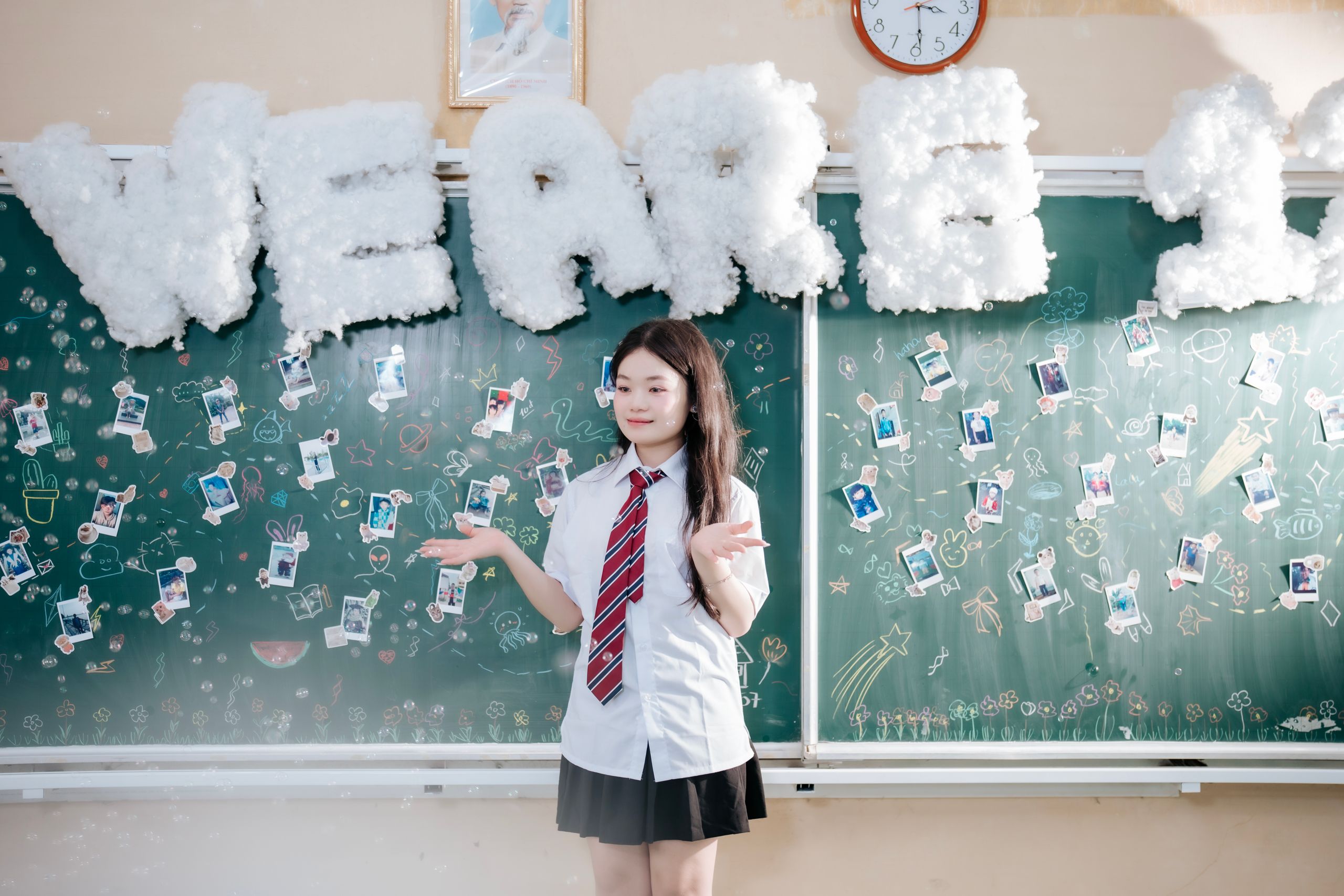 A student poses in front of a decorated chalkboard for a school celebration.