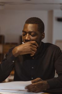 A thoughtful black businessman focusing on paperwork in an office setting.