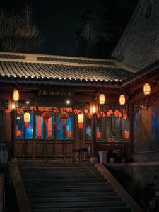 A traditional Asian building adorned with red lanterns beautifully illuminated at night.