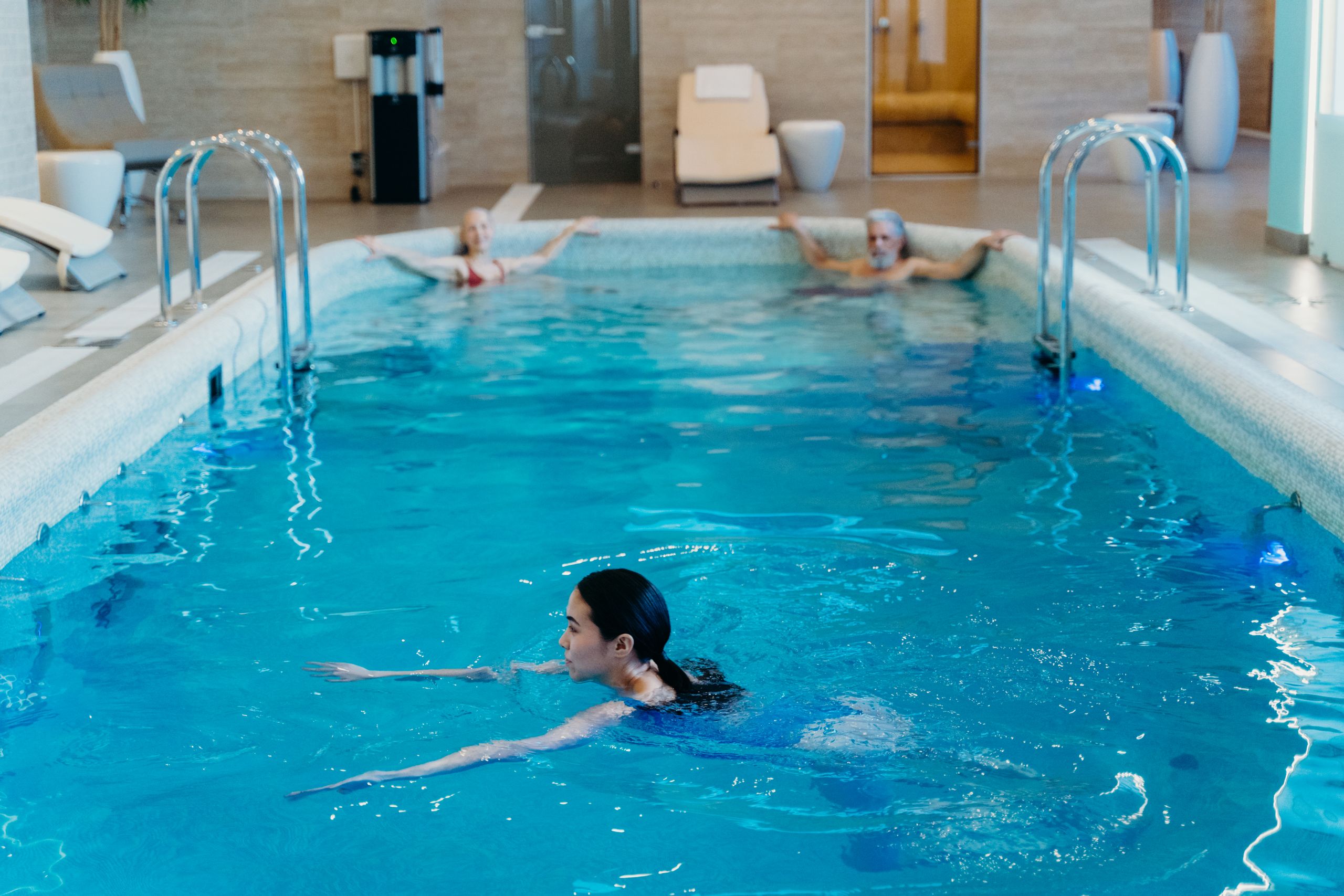 Adults relaxing and swimming in a serene indoor pool setting, perfect for leisure and recreation.