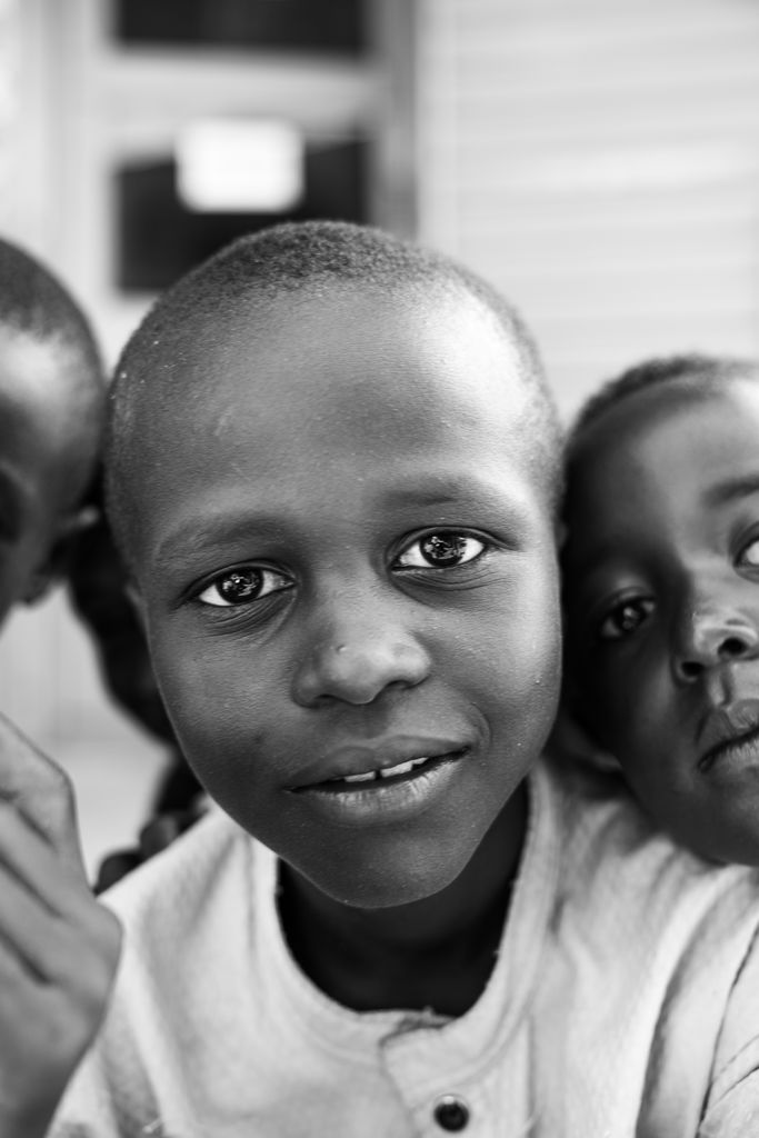 Black and white portrait of two children smiling warmly outdoors.