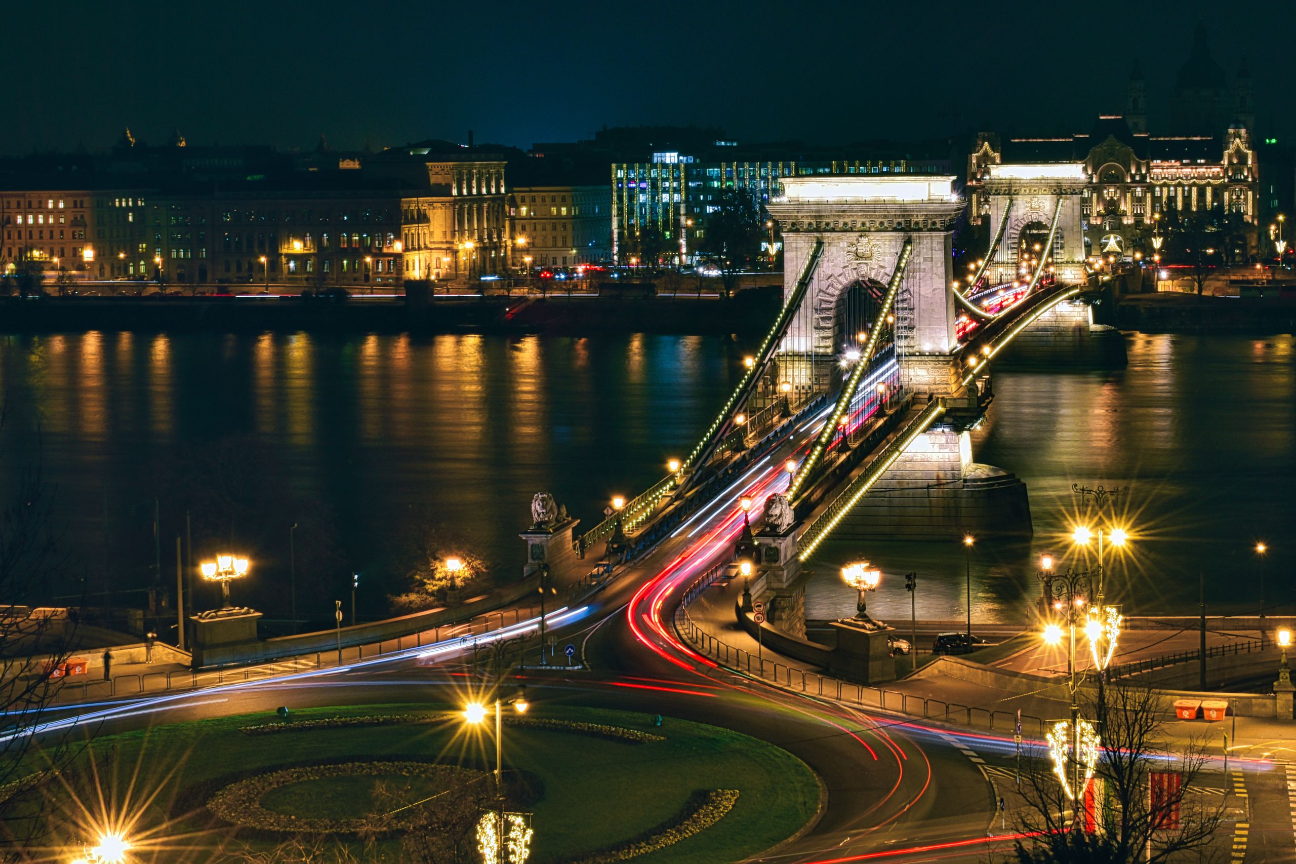Illuminated Széchenyi Chain Bridge shining over the Danube River at night in Budapest.