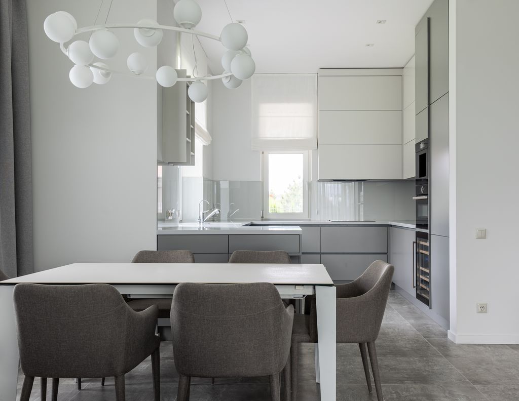 Interior of modern comfortable kitchen with clean white table and soft gray chairs