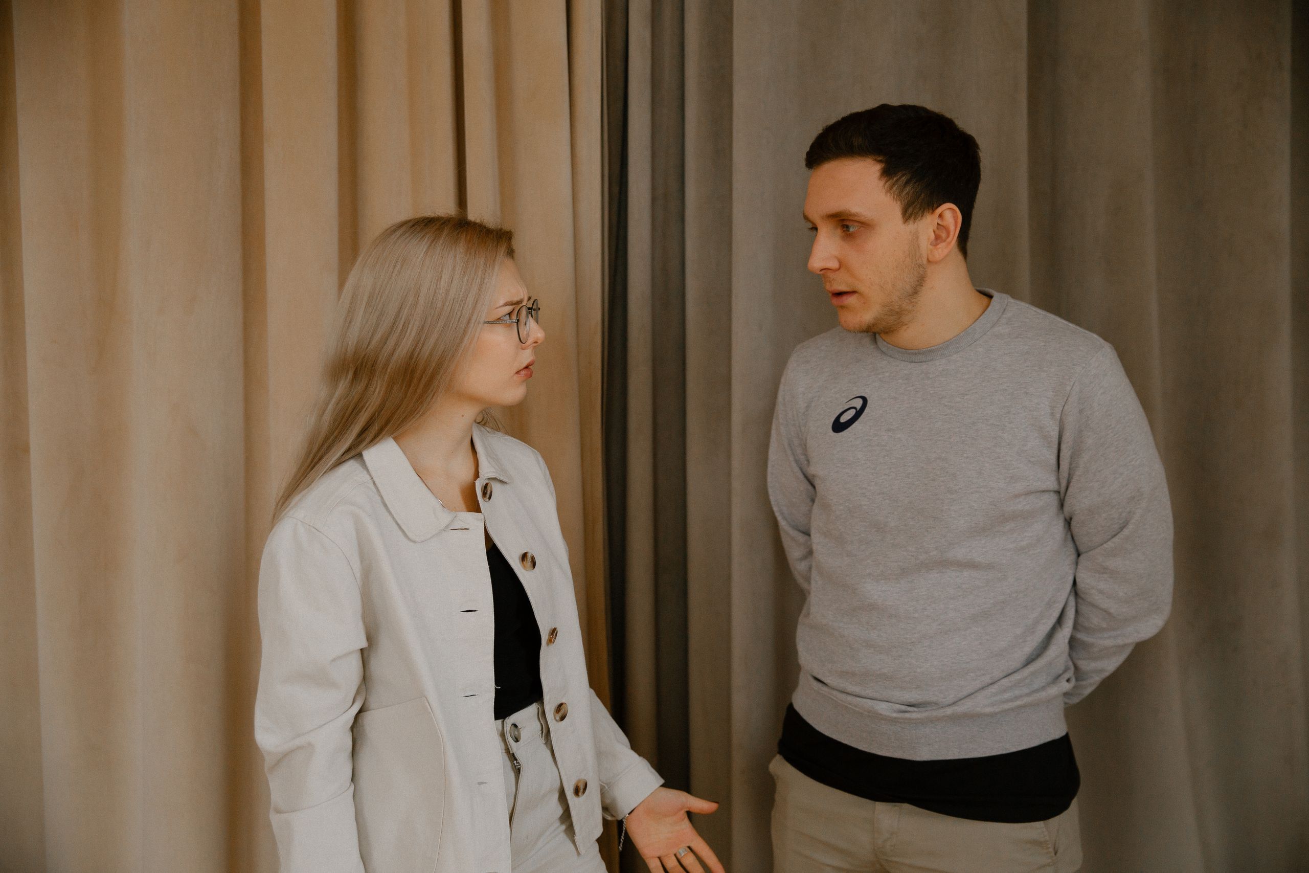 Man and woman having a serious conversation indoors, focused expressions.