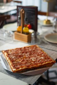 Savory square pepperoni pizza served on a serene and stylish restaurant table.