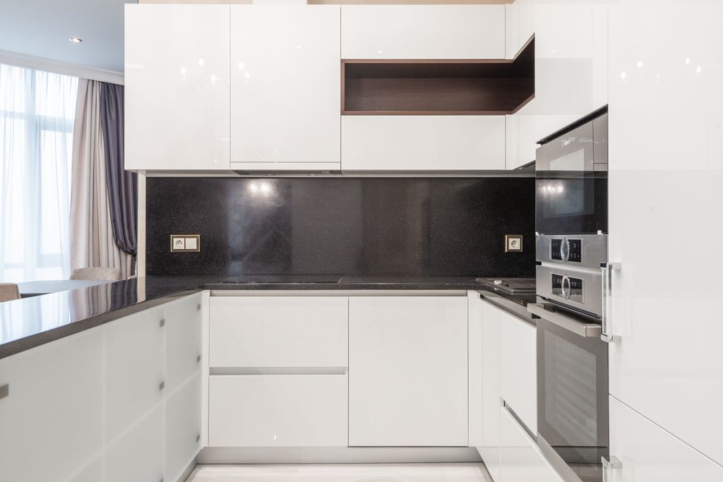 Sleek and clean modern kitchen with minimalist white cabinetry and black accents.