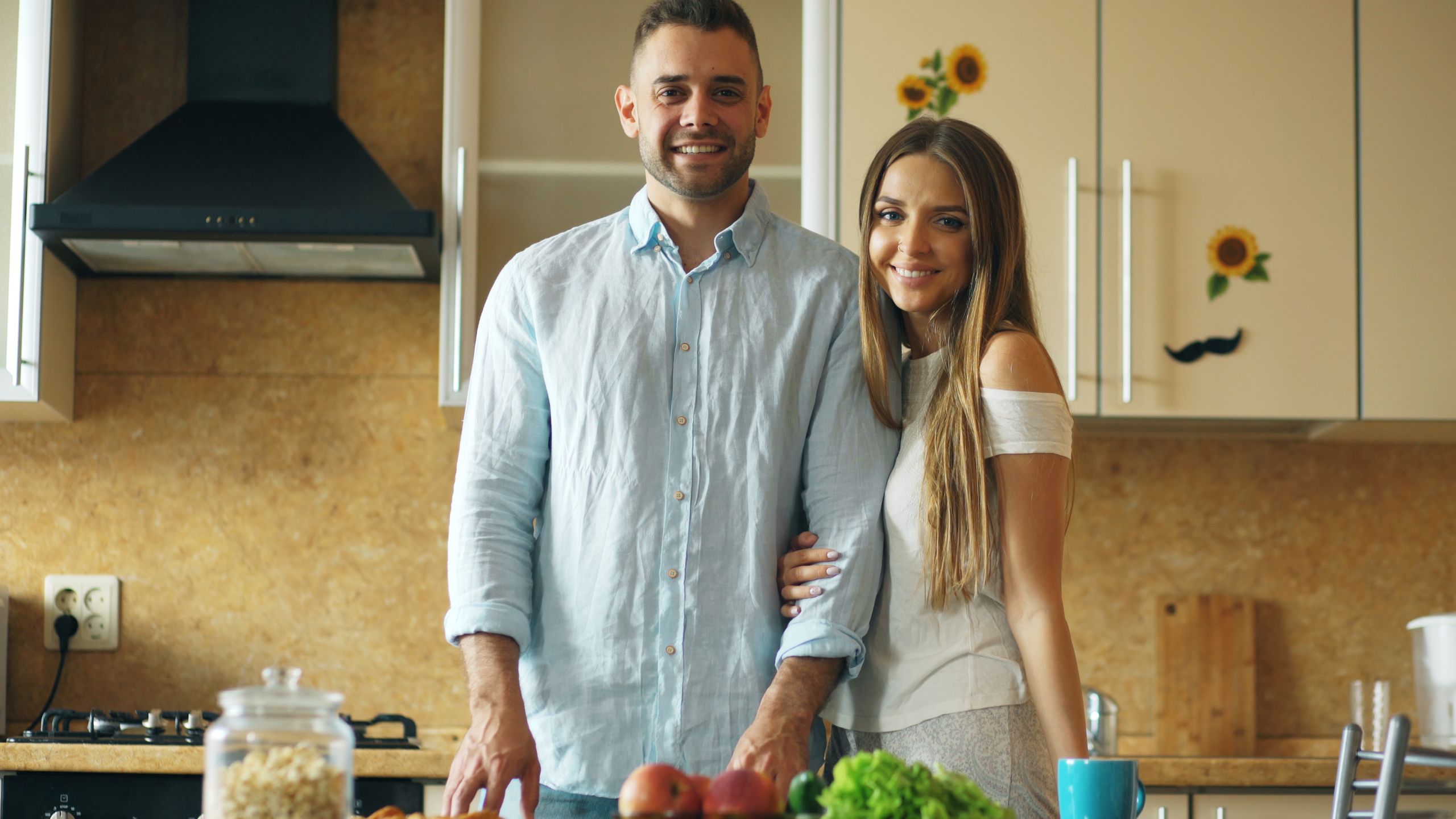 Smiling couple enjoying time together in a modern kitchen environment.