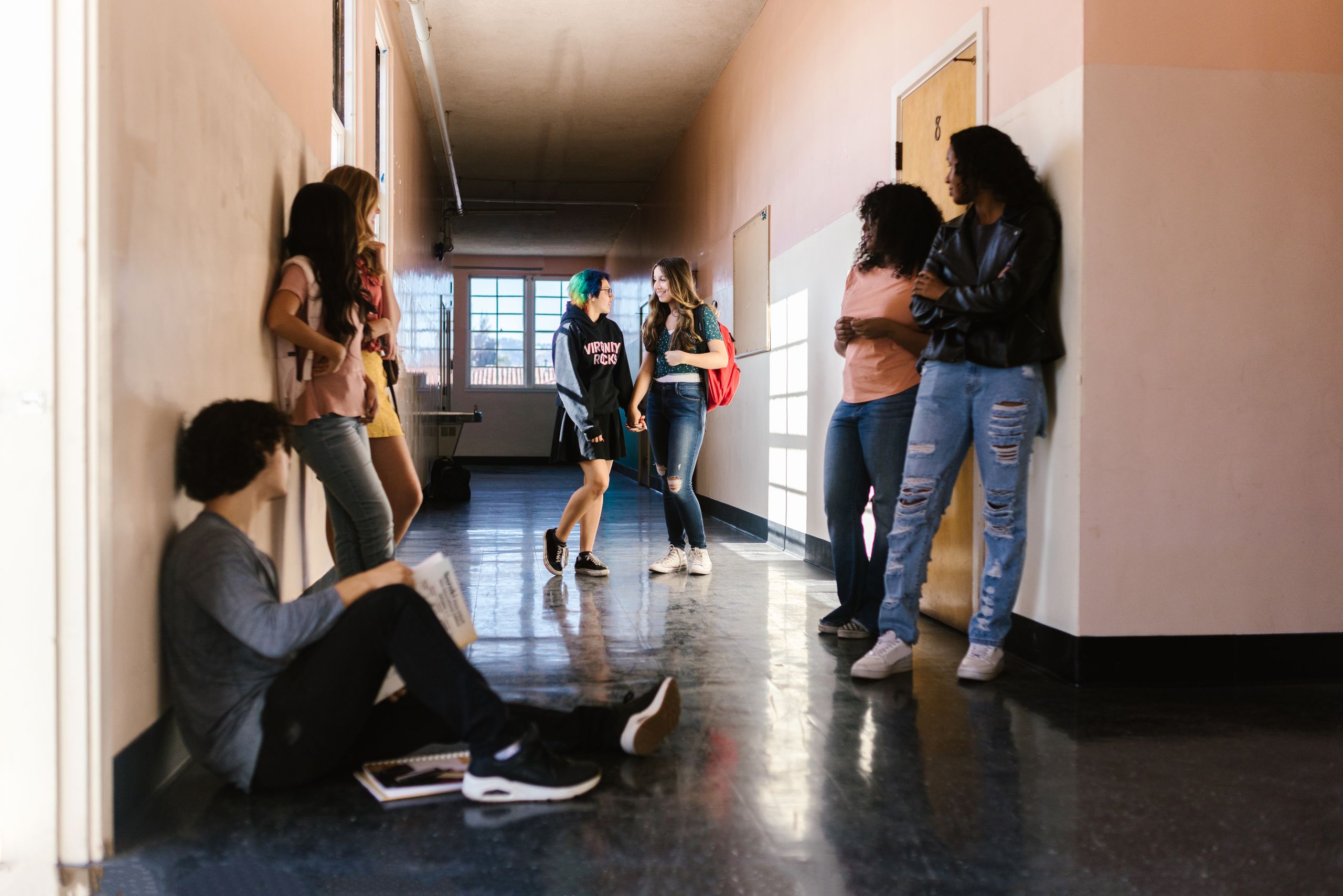 Students interact and relax between classes in a school's bright hallway.