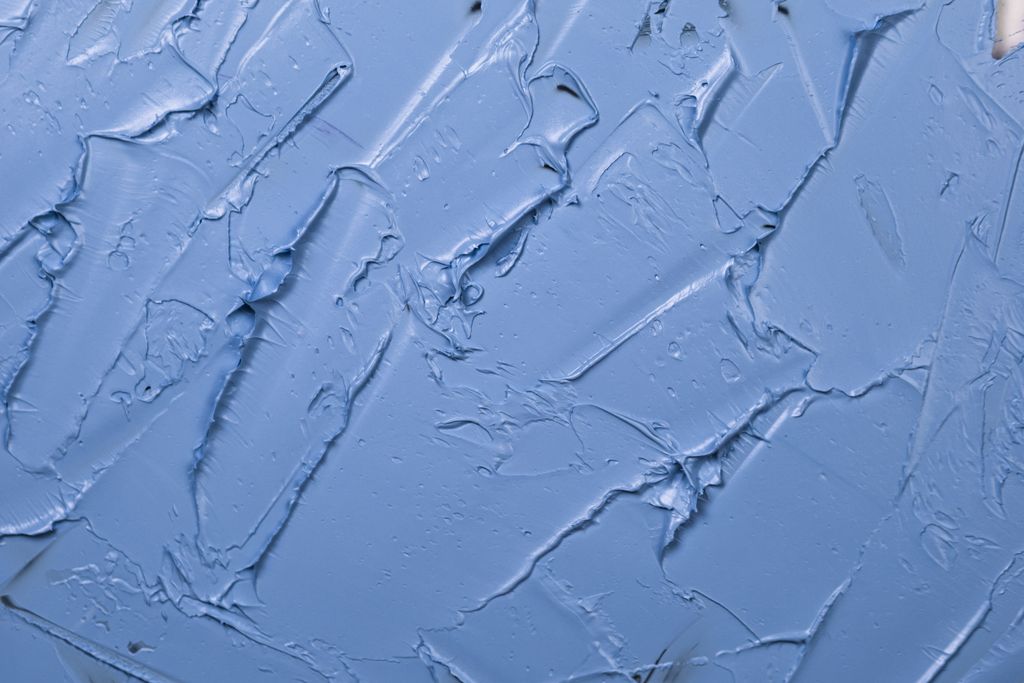 Textured blue paint background showcasing abstract patterns and artistic expression.