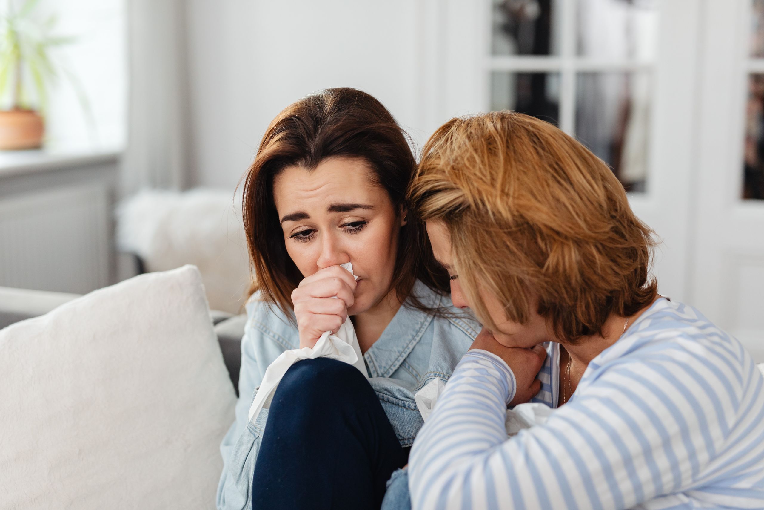 Two women sharing an emotional moment at home, providing comfort and support during a difficult time.