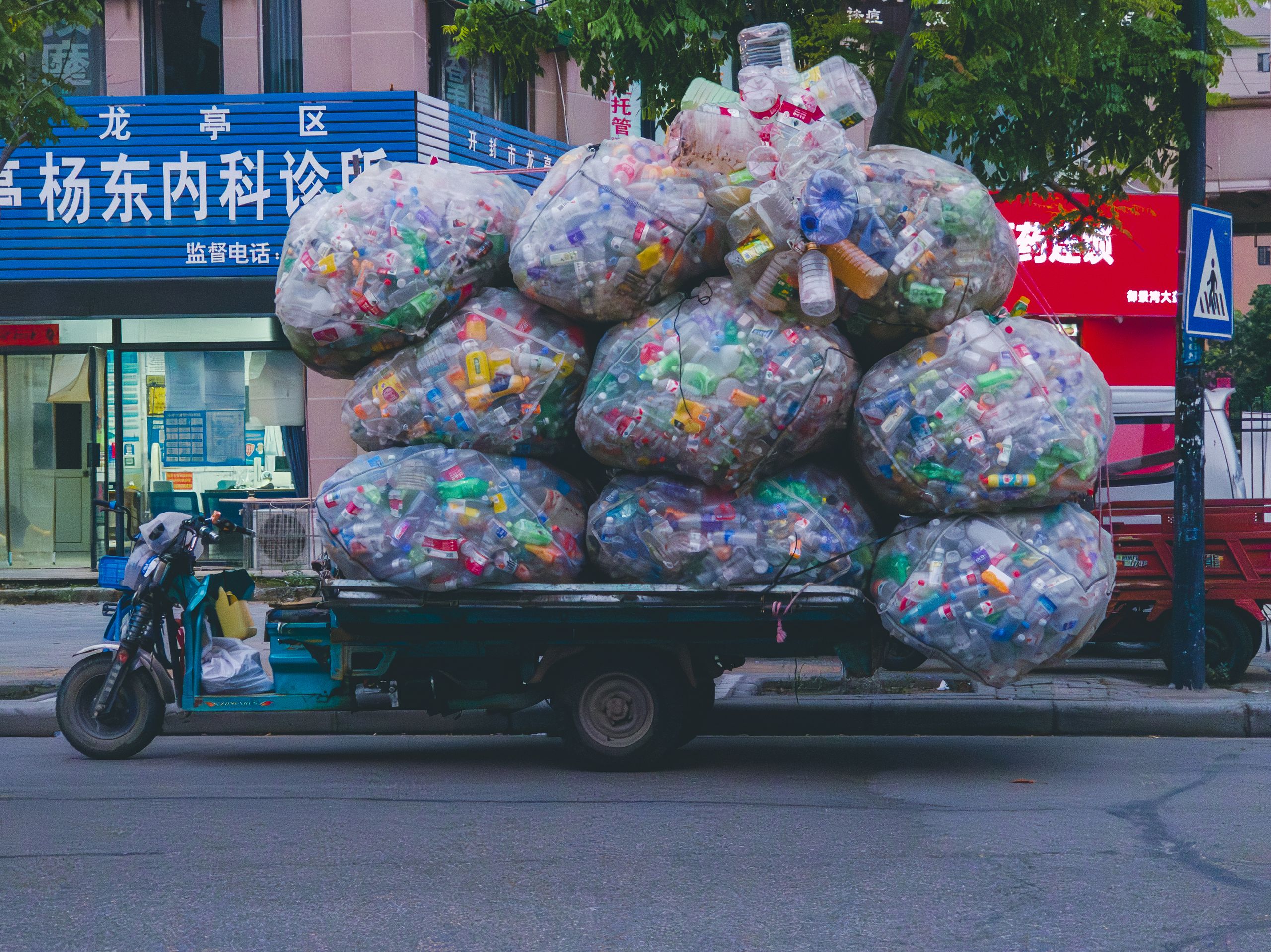 Urban truck loaded with large bags of plastic bottles and recyclables, street scene.