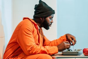 side view of african american prisoner eating in prison cell