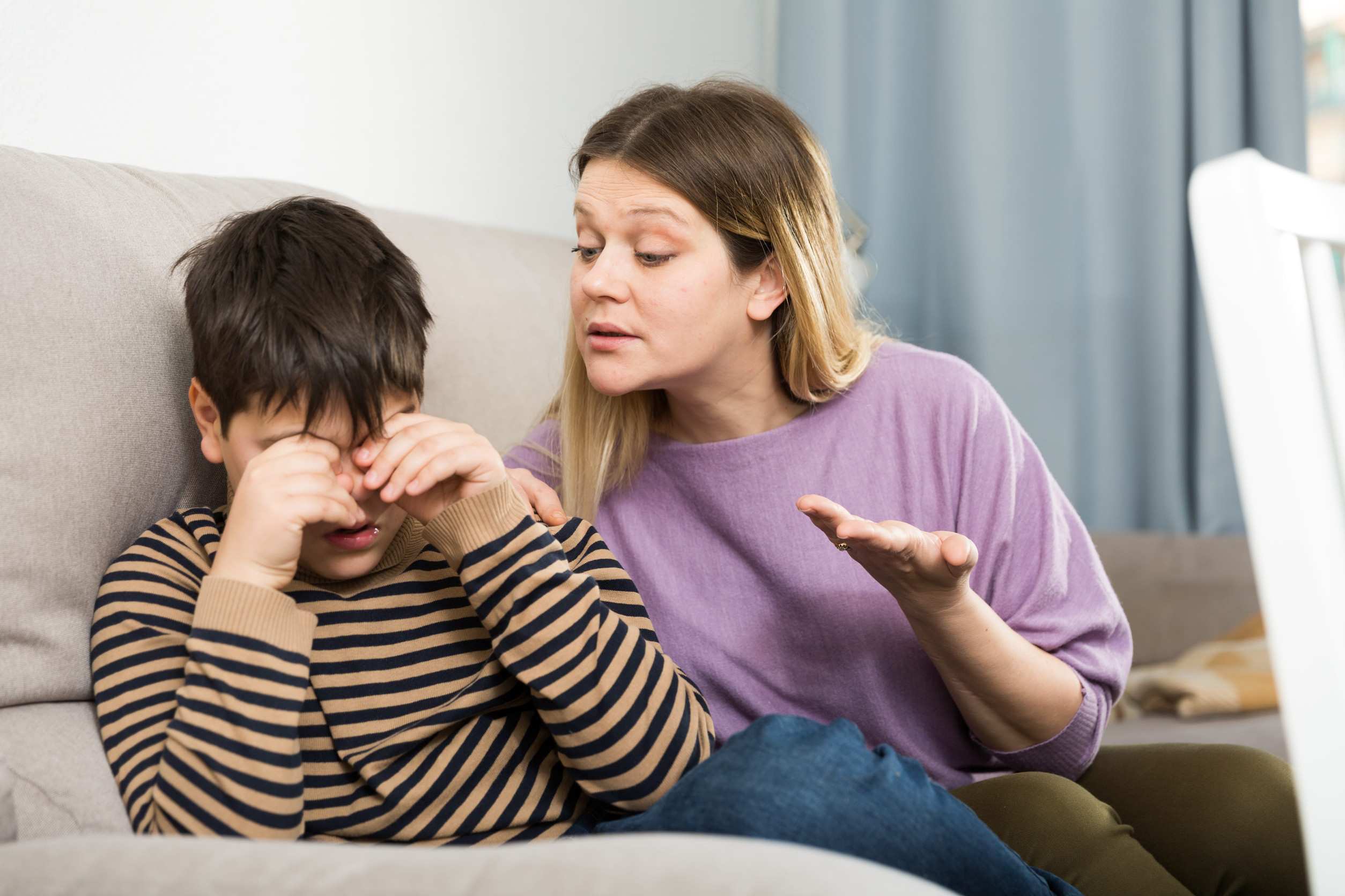 Upset mother and offended son crying during arguing in domestic interior