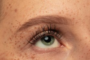 Beautiful young womans eye close-up shot. Female model with well-kept skin. Perfect skincare, human emotions, facial expression, beauty and cosmetics concept. Deep green color and eyebrows.