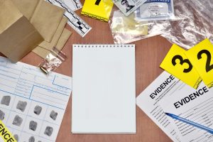 Paperwork during crime scene investigation process in csi laboratory. Evidence labels with fingerprint applicant and many confiscated personal items on wooden table close up