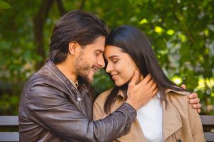 Portrait of beautiful millennial couple cuddling in park
