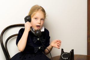 A little girl is ringing on the old phone.